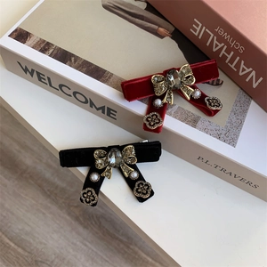 Detailed view of red and black velvet bow hair clips with rhinestones and pearls