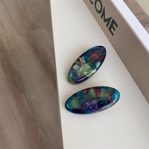 Detail of handmade acetate duckbill hair clip with marble texture and gold lettering