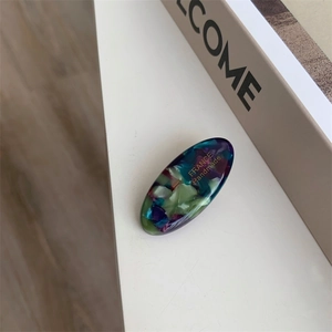 Detail of acetate hair clip with colorful marble pattern and gold France Handmade logo