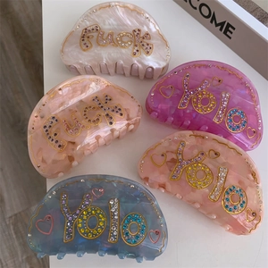 Détail de pinces à cheveux en cinq couleurs avec des strass brillants et des lettres