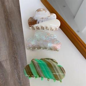 Three cloud-shaped acetate hair claws in marble and pearl textures on white background
