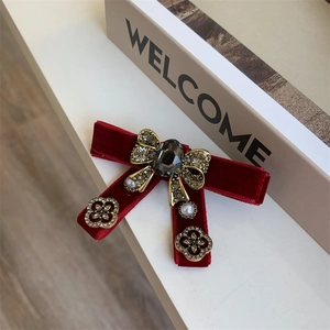 Detailed view of luxury red velvet bow hair clip with crystals and pearl pendant details