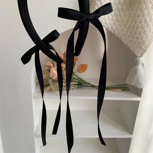 Detail of elegant black ribbon bow headband with long streamers and textured fabric finish