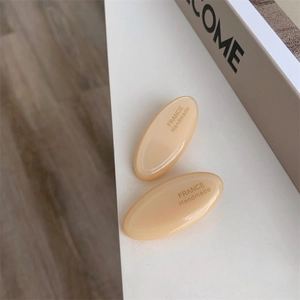 Detailed macro view of cream-colored handmade acetate hair clip with gold lettering