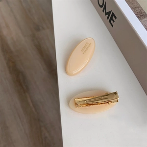 Detail view of oval acetate hair clip with golden metal base and France Handmade text