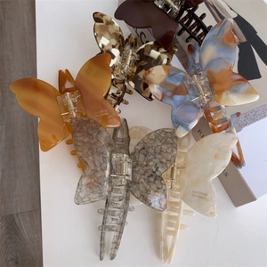 Elegant bow acetate hair claws in various marble textures and amber colors for women