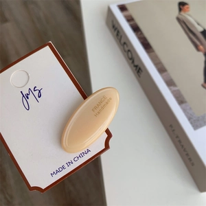 Close-up of beige oval acetate hair clip with France Handmade engraving on card