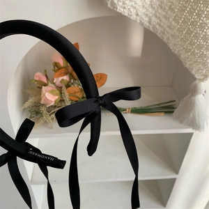Detailed shot of black satin headband featuring handmade ribbons and elegant bows