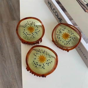 Detail van 3 stuks kiwi haarspelden van acetaat met doorschijnende vruchtvlees texturen