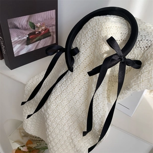 Detail of black ribbon bow headband with thickened sponge design on white knit fabric