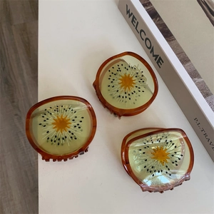 Detail van drie kiwi haarklemmen van acetaat met doorschijnende groene vruchtvlees en textuur