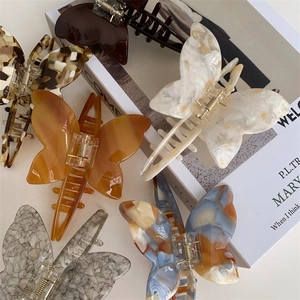 Close-up of assorted tortoiseshell and marble acetate butterfly hair claws on a magazine