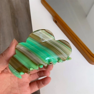 Detail of cloud-shaped acetate hair claw featuring green and brown marble texture
