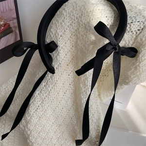 Close-up of elegant black ballet-style headband with long satin ribbon bows on knit background