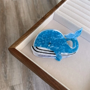 Détail de la pince à cheveux en acétate marbré bleu en forme de baleine sur plateau