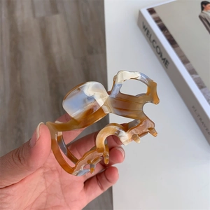 Detail shot of amber marble acetate hair claw clip with a glossy resin texture and spring