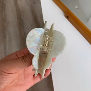 Detail view of the durable golden metal spring mechanism on a cream marble acetate hair claw