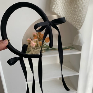 Close-up of black satin bow headband with handmade label and long elegant ribbons