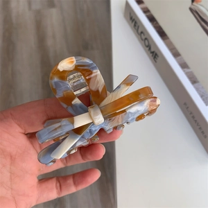 Detail of marble pattern acetate claw clip with 3D bow design and sturdy silver spring