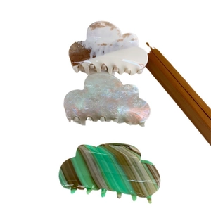 Three acetate cloud-shaped hair claws in marble, pearlescent, and green patterns