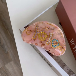 Détail de la pince à cheveux en acétate rose avec strass colorés et inscription YOLO