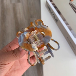 Detail showing the amber marble texture of the acetate hair claw with a gold metal spring