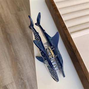 Détail de la pince à cheveux en acétate bleu en forme de baleine à pois blancs et ressort doré