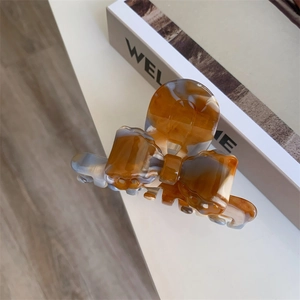 Detail view of acetate claw clip with marble texture and cute bow shape design