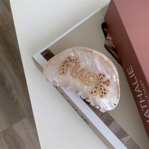 Détail d'une pince à cheveux en acétate rose avec strass en cristal sur une table
