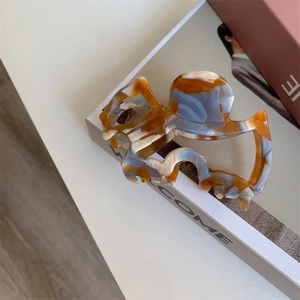 Detail of artistic marble pattern acetate hair claw clip with vintage brown textures