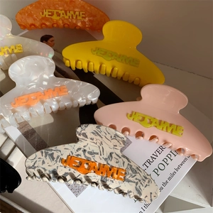 Close-up of acetate hair claws with embossed Je T'aime lettering in vibrant colors