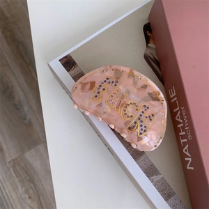 Détail de la pince à cheveux en acétate rose avec motif de lettres en strass brillant
