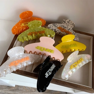 Detailed macro view of colorful acetate hair claws with embossed JE T'AIME lettering text