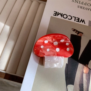 Detailed view of the red mushroom hair claw clip made of acetic acid on a fashion magazine