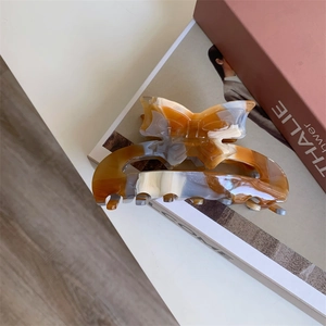 Detailed macro view of an amber marble acetate hair claw clip with a 3D bow design