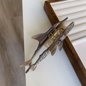 Vue de dessus d'une pince à cheveux créative en forme de requin avec des pois blancs