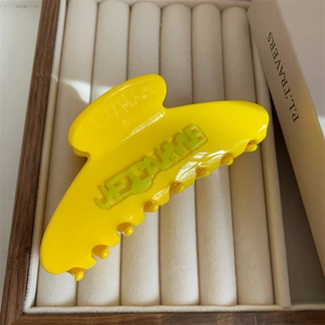 Close-up of a yellow acetate hair claw clip with JE T'AIME embossed green lettering