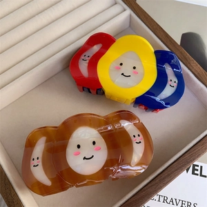 Détail de pinces à cheveux tricolores et ambrées avec décorations de visage souriant