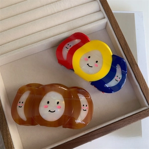 Détail de pinces à cheveux tricolores et ambre avec smiley sur velours beige doux