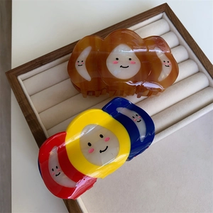 Détail de pinces à cheveux tricolores et ambrées avec smileys sur un plateau en velours