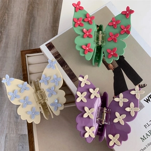 Détail de trois pinces à cheveux papillon en différentes couleurs avec ornements floraux