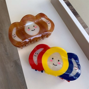 Détail de grandes pinces à cheveux tricolores avec motifs de nuages souriants mignons