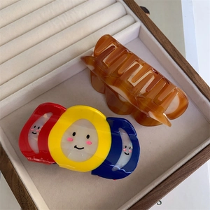 Détail de la pince à cheveux tricolore à smiley et de la pince ondulée ambrée