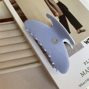 Détail d'une pince à cheveux lavande pailletée posée sur un magazine de mode