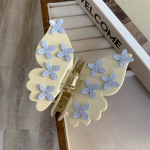 Détail de la pince à cheveux papillon avec finition crème et fleurs bleues à strass
