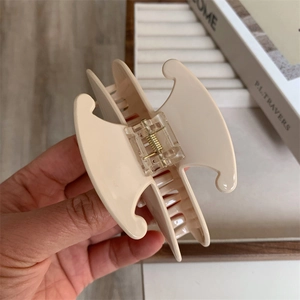 Détail d'une grande pince à cheveux en acétate crème avec un ressort en métal doré