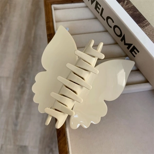 Détail d'une grande pince à cheveux papillon en acétate crème aux bords ondulés chic