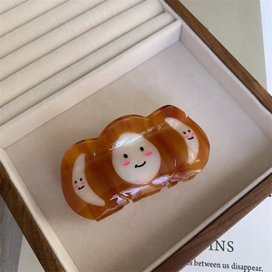 Détail d'une grande pince à cheveux ambre en écaille avec un motif blanc souriant mignon