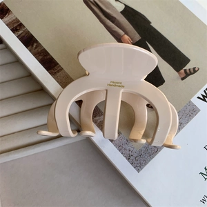 Close-up of beige acetate shark hair claw with gold France Handmade lettering