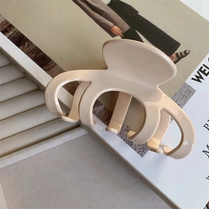 Top view of large cream acetate hair claw clip with glossy finish on fashion magazine